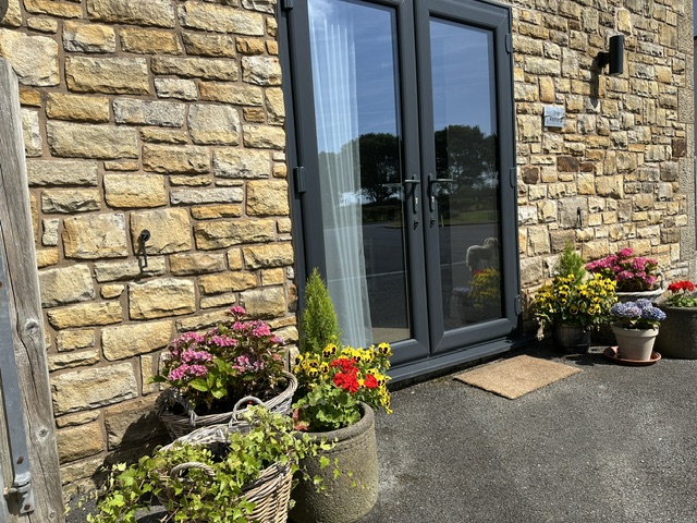 The Retreat entrance, with stone walls and colourful flowers
